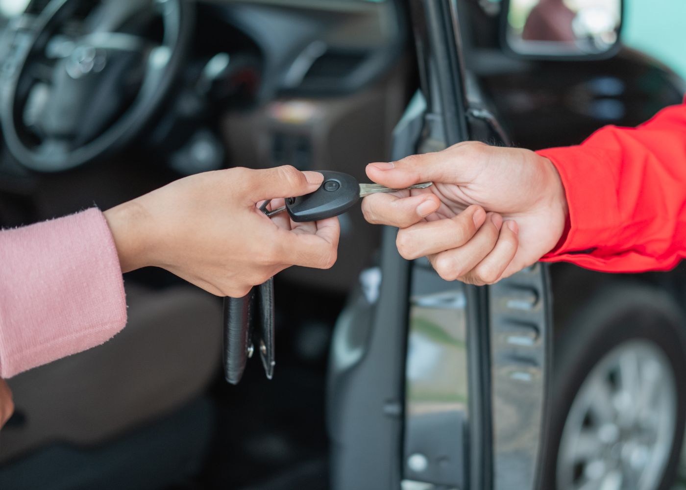 Mujer comprando coche de segunda mano después de leer consejos sobre que mirar. Hombre la hace entrega de las llaves
